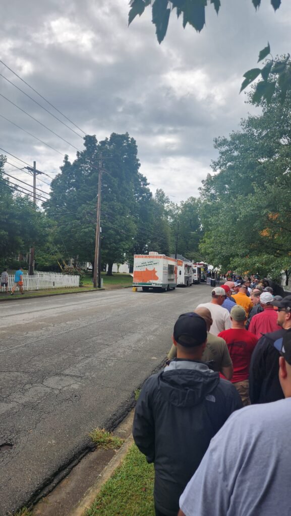 Line of people with food trucks in the distance.