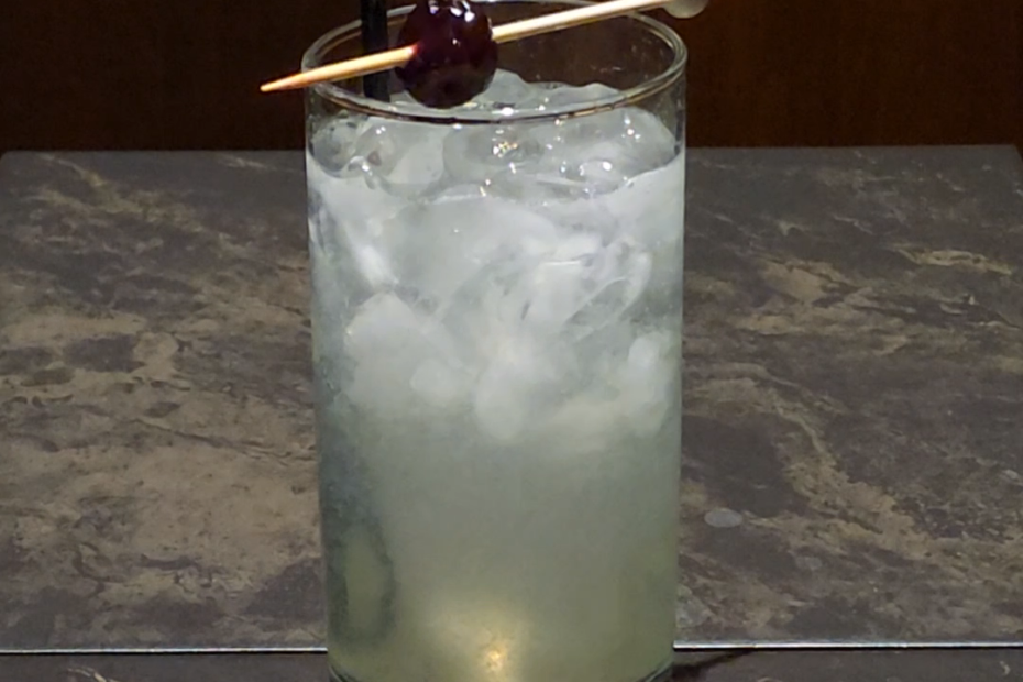 cherry on top of a Collins glass with a cocktail