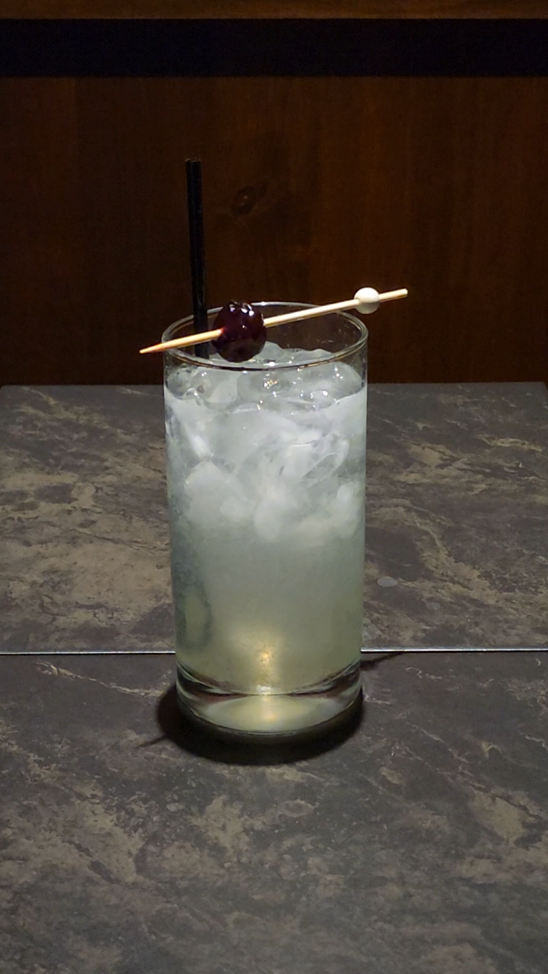 cherry on top of a Collins glass with a cocktail